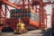 View from the ground to a huge port crane loading container ship. Tractors and loading platforms involved in the loading