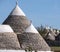 View of group of traditional round dry stone trulli houses with conical roofs outside Alberobello, Puglia Italy.