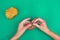 View of hands, making a crochet pattern on green background with a hook.