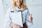 View of happy blonde woman holding clipboard with resume letters and showing thumb up