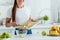 View of happy young woman putting sliced green apple in bowl