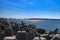 View of a harbor over modular concrete block ripraps in foreground and port in background on sunny day. Port harbor