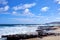 View of Hawaiian ocean with strong waves, beautiful clouds, and rocks scattered on the beach