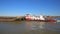 View on HGK pusher boat herkules vessel with cargo barge on river waal against blue sky