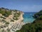 View from the high shore to the sandy beach in the bay of Cala Antena