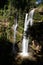 View of a high waterfall with sunlight and surrounded by rainforest