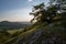 view of hill meadows and Spiš Castle in the Slovak Little Carpathian Mountains with the setting sun in the background