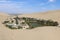 View of the Huacachina village and oasis from a nearby sand dune on a sunny day in southwestern Peru