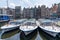 View of the iconic houses on the waterfront at the Damrak in downtown Amsterdam with city tour tourist boats in the foreground