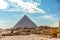 View of the incredibly majestic pyramid of the cheops on a sunny day in the desert with ancient ruins