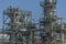 View at the industrial complex of oil refinery and people working in, with buildings, equipment and machinery, blue sky background