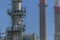 View at the industrial complex of oil refinery and people working in, with buildings, equipment and machinery, blue sky background