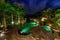 View of infinity swimming pool at luxurious jungle villa. Beautiful garden by night