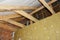 A view from inside a house attic construction on unfinished roof with wooden frame, roof beams, rafters, ceiling joists, trusses,