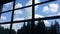 View from inside  of an office building through a large window  at the sky with  clouds and at a forest