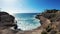 View of the island's round sea bay. Azure waves crash against the stone shore. Palm trees bend in strong winds along the