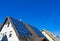 View on isolated german roof with solar panels against clear blue sky - Germany