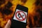 View on isolated mobile phone with fire not allowed sign. Blurred flames background. Focus on right upper part of symbol