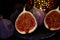 View on isolated raw ripe fig half with group of figs  on black slate stone illuminated by oriental candle lamp