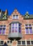 View on isolated red brick facade of medieval belgian house, gabled roof, bay window, clear blue sky