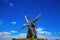 View on isolated typical dutch windmill Molen de grauwe beer in rural landscape against deep blue summer sky with cumulus clouds