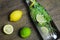 View on isolated water glass bottle flavored with mint leaves and yellow citrus, green lime fruit on wood table focus on bottle