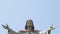 View of Jesus Christ with open arms shifting to cloudless sky, vertical panorama