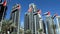 View of JLT skyscrapers with UAE flags. United Arab Emirates flags waving on blue sky background. National day. Group of UAE flags