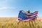 View of kid in straw hat holding american flag in golden field