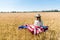 View of kid in straw hat holding american flag in golden field in summertime