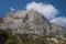 View of Kush Kaya mountain against the blue sky. Rocky mountain and green forest at its base.