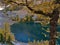 View of Lake Agnes with shimmering water viewed through the yellow branches of larch tree in autumn in Banff National Park.