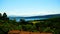 View of Lake Bracciano from a height with plants and trees and roofs with tiles in the foreground