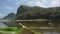 The view of the lake is shallow with lots of rocks and has a murky water color and also mountains that rise very high and overgrow