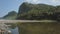 The view of the lake is shallow with lots of rocks and has a murky water color and also mountains that rise very high and overgrow