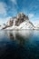 View of a landscape of a Norwegian fjord with a snowy mountain reflecting in the water. At the foot of the mountain a small