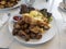 View of a large breakfast spread of eggs benedict, fingerling potatoes, and turkey sausage patties on a marble table in