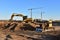 View on the large construction site with tower cranes and buildings on blue background. Excavator and dozer working on eartwork .