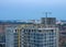 View on the large construction site at urban area in the evening. Tower cranes in action with machinery and builders. Multi-storey