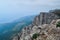 view of large steep rock cliff, backdrop of Black sea coast in Crimea, city and forest below