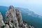 View from large steep sharp stone rock Ai-petri with green trees stands on a cliff against the background of Black sea coastline