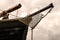 A view of a large wooden schooner`s bow under the cloudy sky.