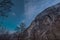 View from the Lauterbrunnen valley towards epic stone rock walls rising up from the valley. Dark blue skies