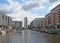 a view of of leeds dock with modern apartment developments and bars with moored houseboats and blue cloudy sky