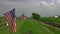 View of a Line of Gently Waving American Flag on a Fence by Farmlands as a Steam Passenger Train Blowing Smoke Approaches in the D