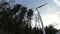 View on lonely electric windmill on the edge of forest. View from down to up.