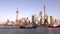 View on Lujiazui skyline and Huangpu river with barges at sunset, Shanghai, China