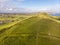 A view of the Lulworth Cove hill along the Jurrassic Coast in Dorset under a majestic blue sky and some white clouds