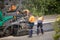 View of machinery and workers laying new bitumen on a suburban road near Hobart