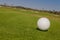 View of macro golf ball and the green golf course background